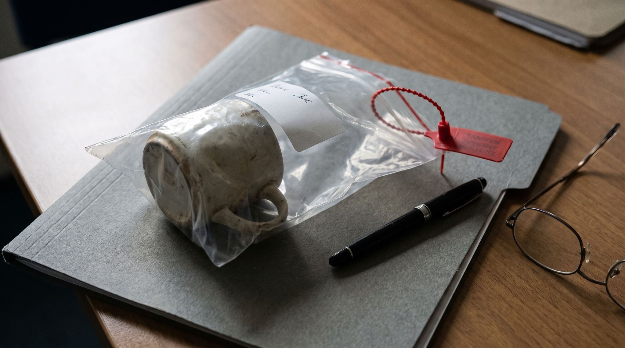 Ceramic mug sealed in a transparent bag with a red seal, placed on a gray file