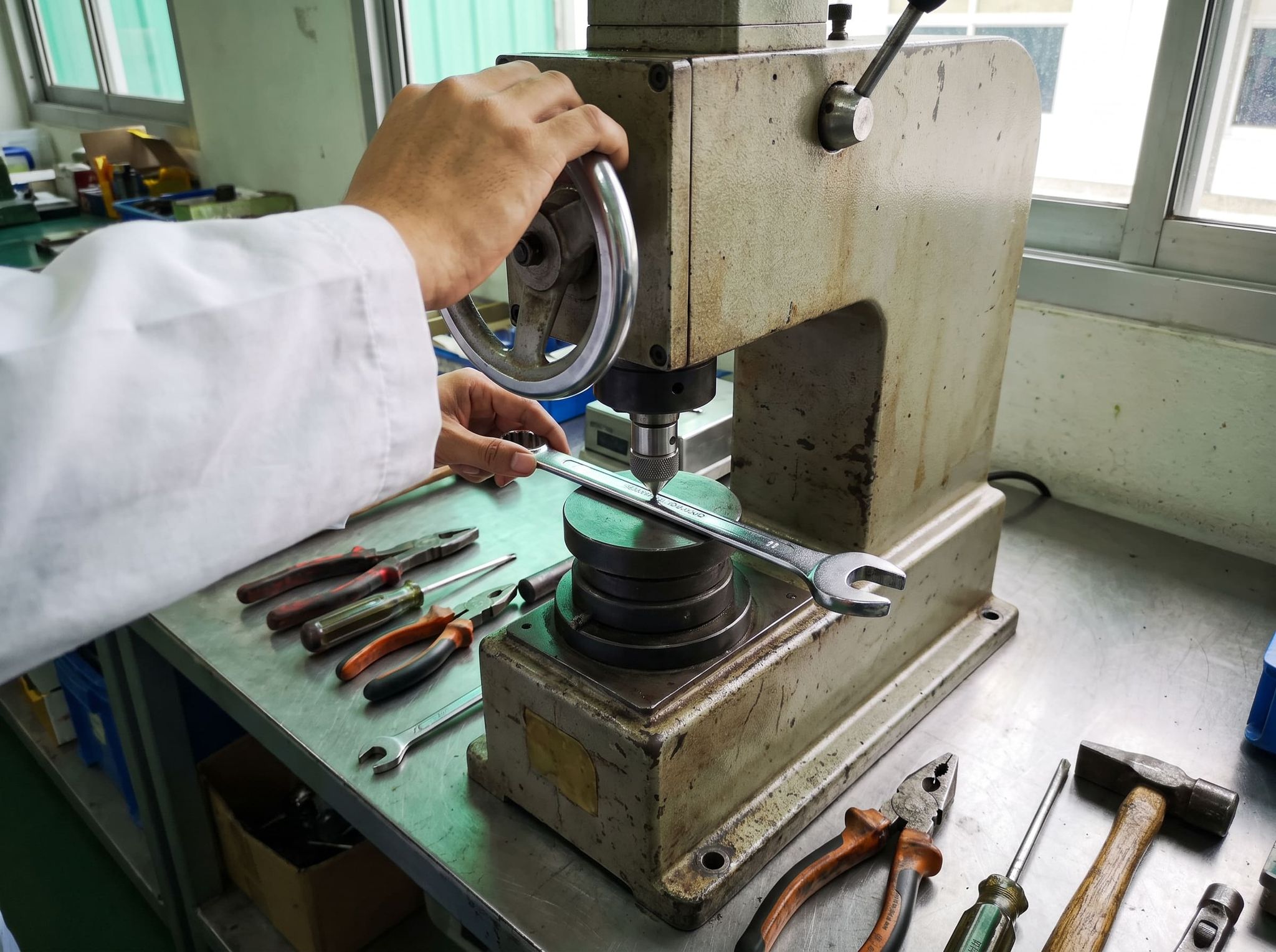 Hardness test on a chrome combination wrench: the penetrator touches the flat of the handle, one hand turns the wheel