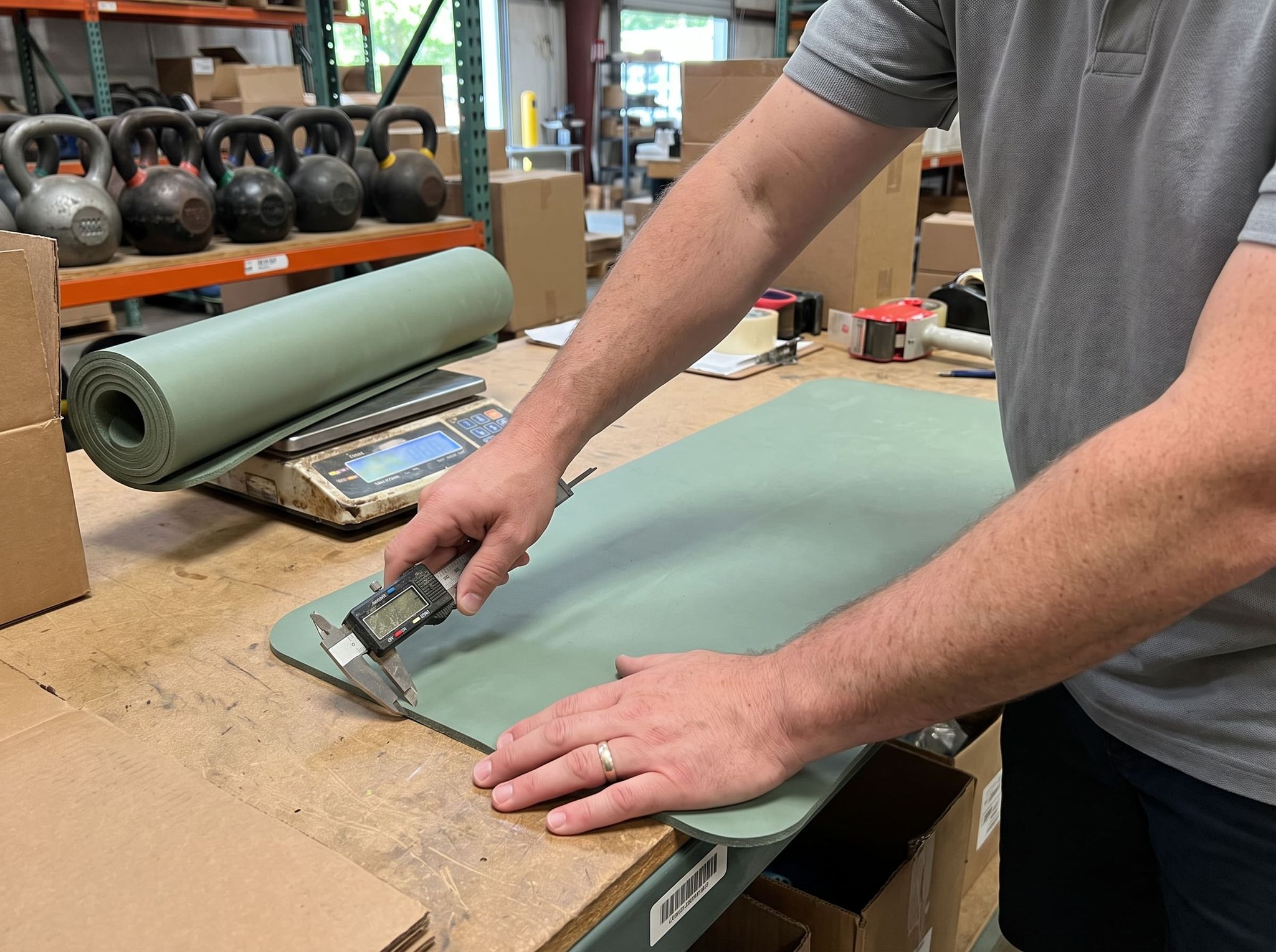 Digital caliper resting on the edge of a sage green yoga mat, the other hand holding the mat flat