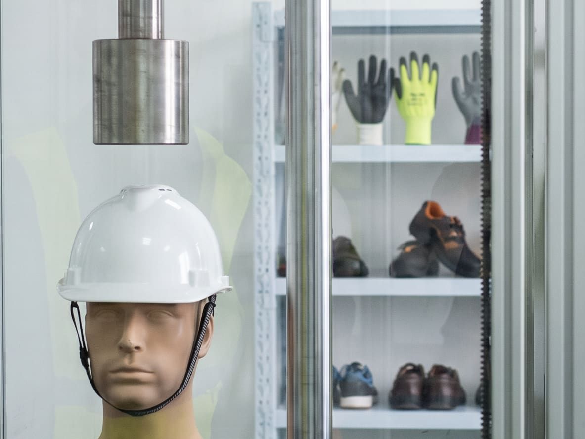 Safety helmet on a dummy head, under the striker of a test rig
